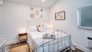A bedroom with a white bed, bedside tables, and a window with blinds. - Cozy Studio Just 5 Minutes from Miami Airport! Comes with 1 Free Parking Space. (Miami Springs)