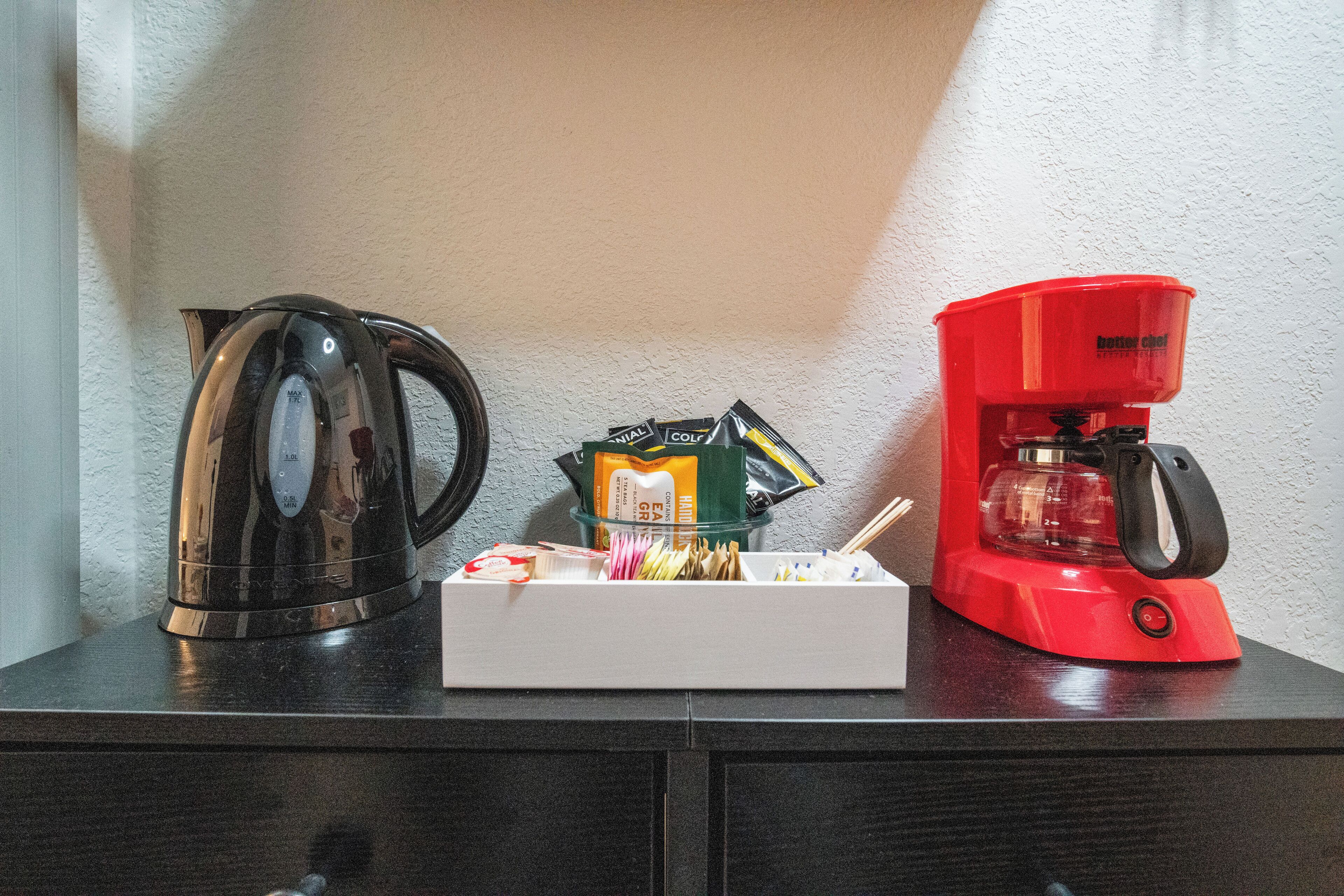 Eine Küchenarbeitsplatte mit einem Wasserkocher, einer Kaffeemaschine und einer Packung Teebeuteln.
