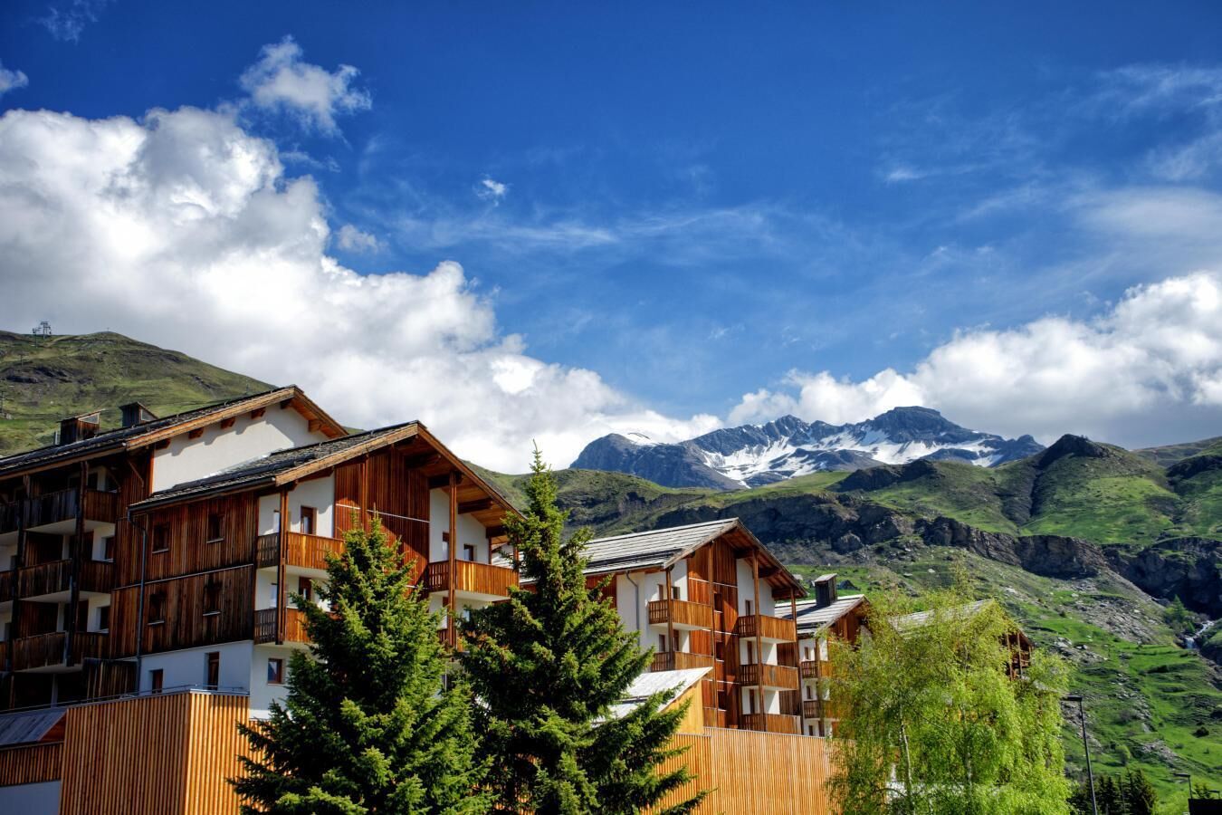 Un chalet de montagne à l’architecture en bois, doté de nombreux balcons et offrant une vue sur des montagnes enneigées.