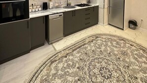 Una cocina moderna con armarios oscuros, un refrigerador de acero inoxidable, un horno empotrado y una alfombra estampada.