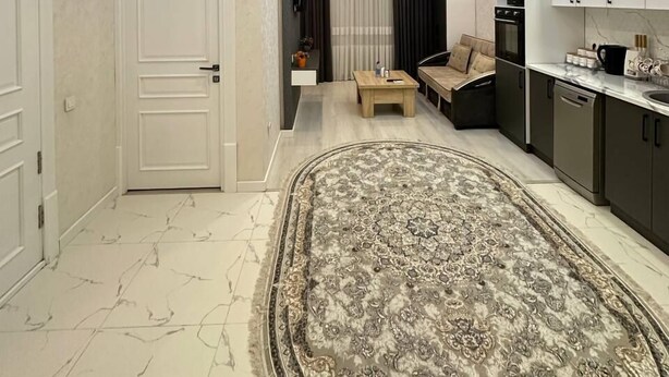 Una cocina moderna con electrodomésticos integrados, una zona de comedor con un sofá y una alfombra estampada.