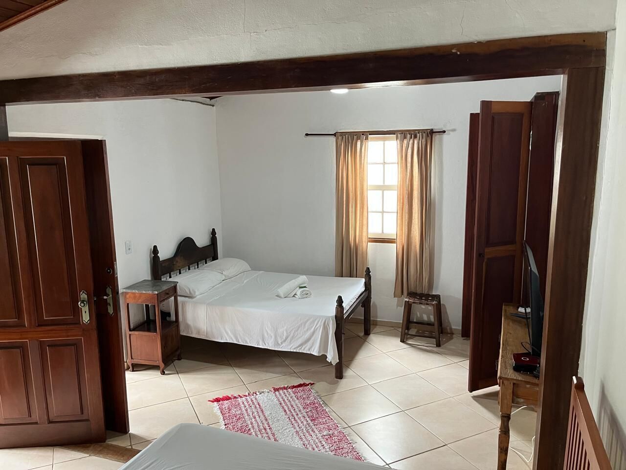 A bedroom with a bed, bedside table, and a small stool.