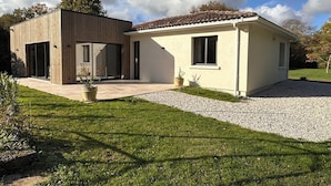 A modern two-story house with a large patio, a wooden deck, and a small garden area. - Villa with swimming pool on the Angoulême golf course (Angoulême)