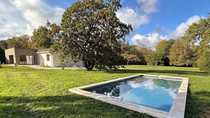 A swimming pool with a stone border, surrounded by a well-maintained lawn and a large tree. - Villa with swimming pool on the Angoulême golf course (Angoulême)