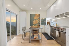 Cozinha moderna com área de refeições, uma janela grande com vista para as montanhas e um quadro na parede.