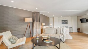 A modern living room with a sofa, a coffee table, a lamp, and a TV mounted on the wall.