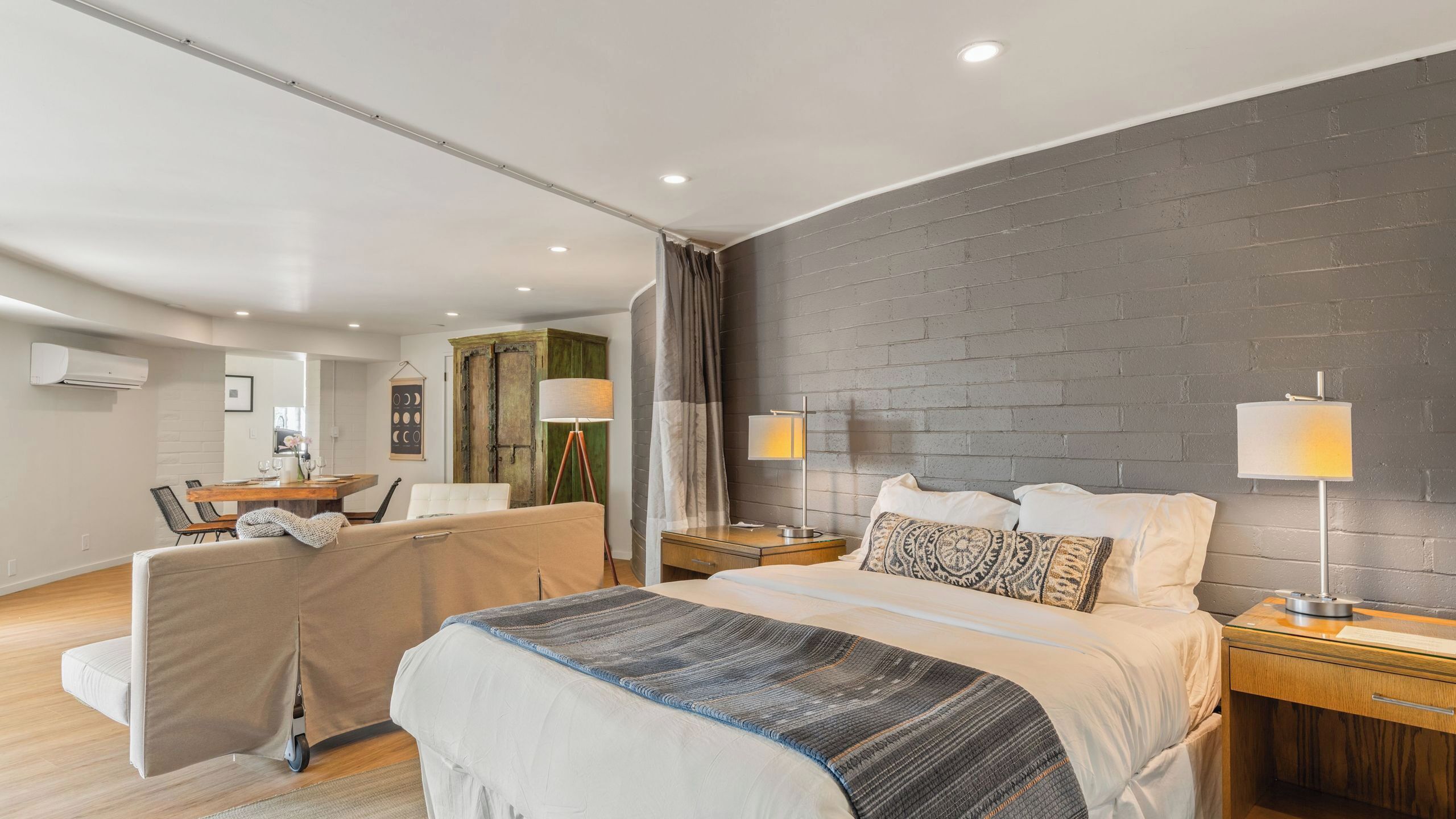 A modern hotel room with a large bed, bedside tables, a desk, and a chair.