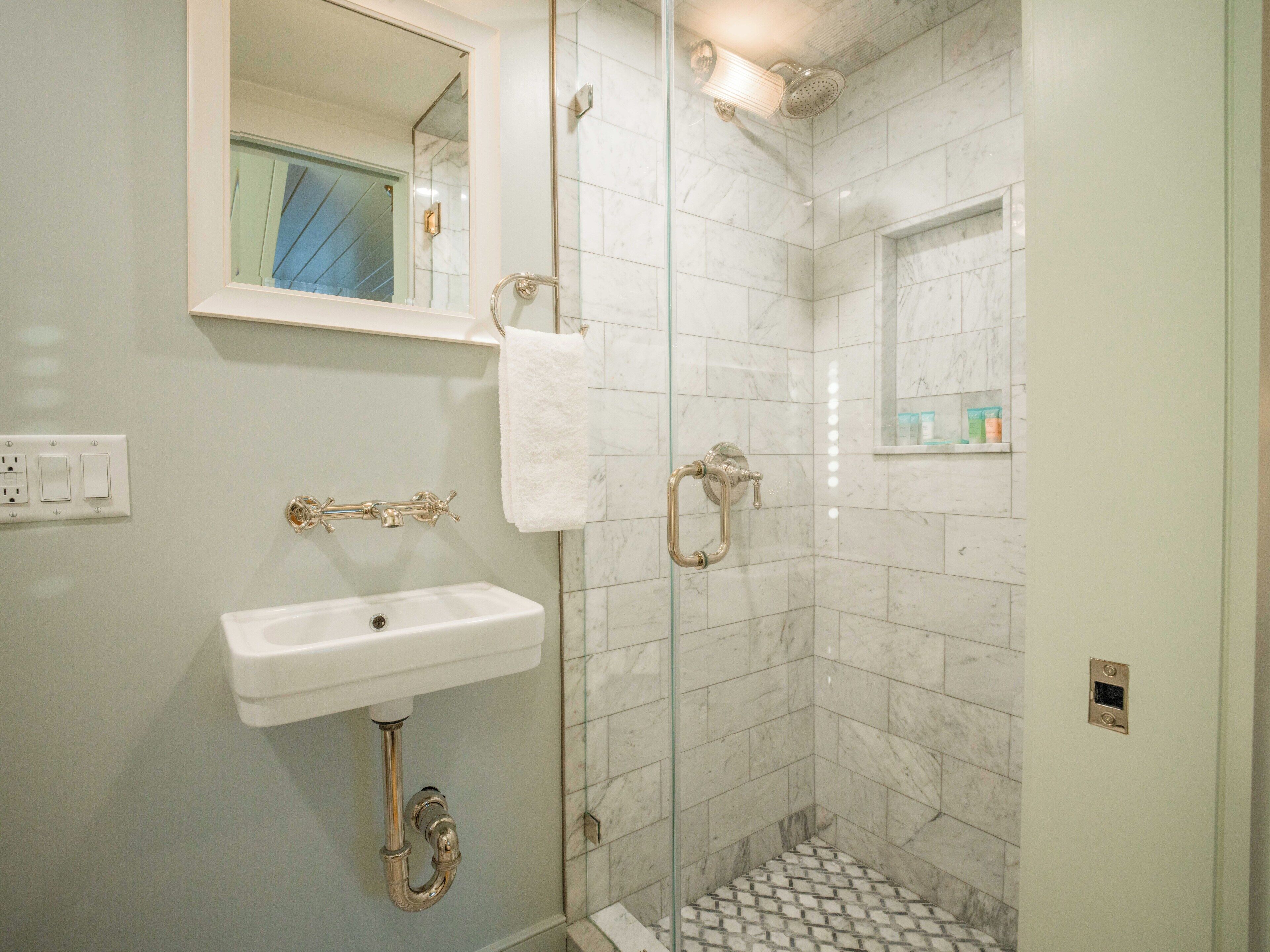Une salle de bain avec une douche à parois de verre, un lavabo blanc et un miroir au-dessus.