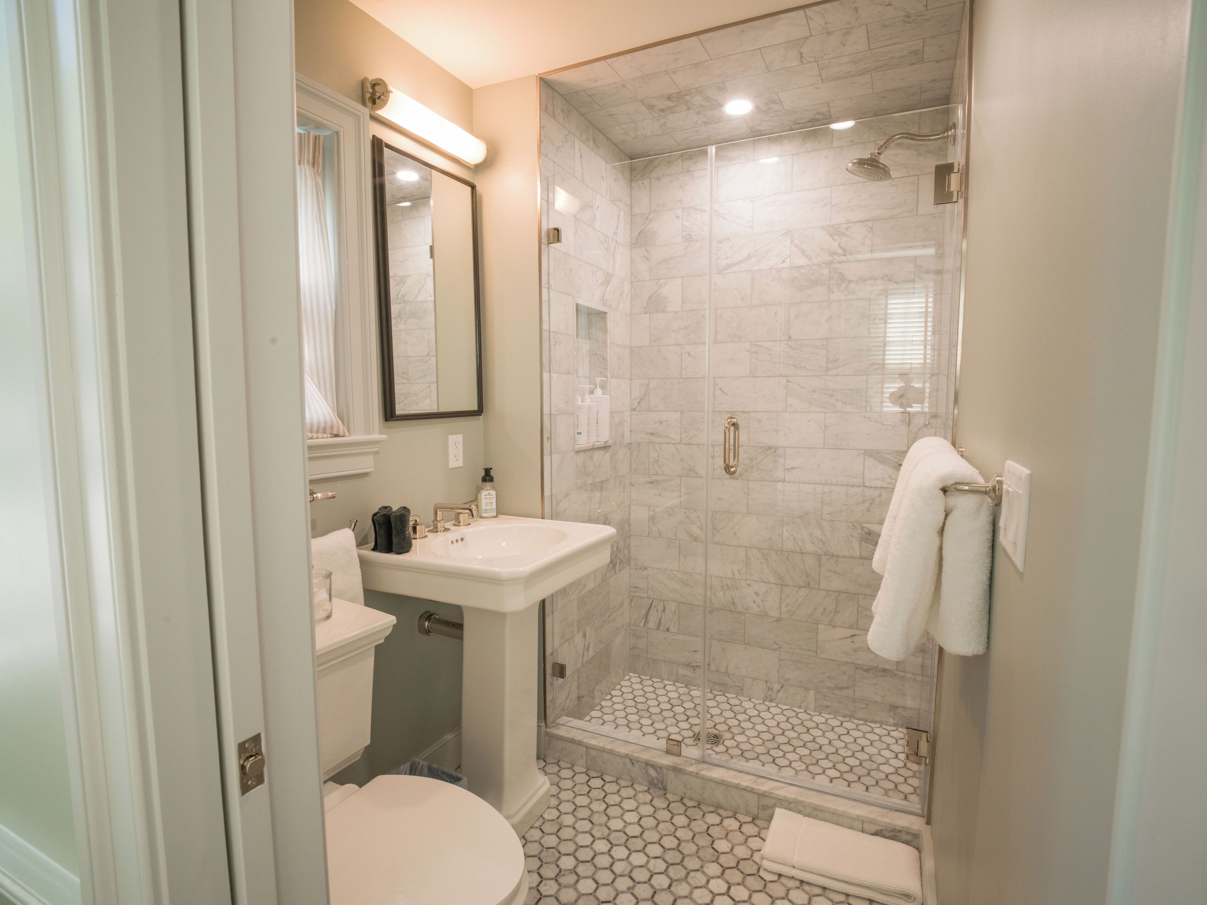 A bathroom with a toilet, sink, shower, and tiled floor.