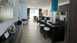 A modern kitchen with a bar area, wooden flooring, and a large painting on the wall. - LUXOR & CONDO OJOS ESPAÑOLES (Chapala)