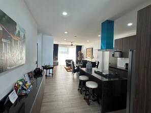 A modern kitchen with a bar area, wooden flooring, and a large painting on the wall. - LUXOR & CONDO OJOS ESPAÑOLES (Chapala)