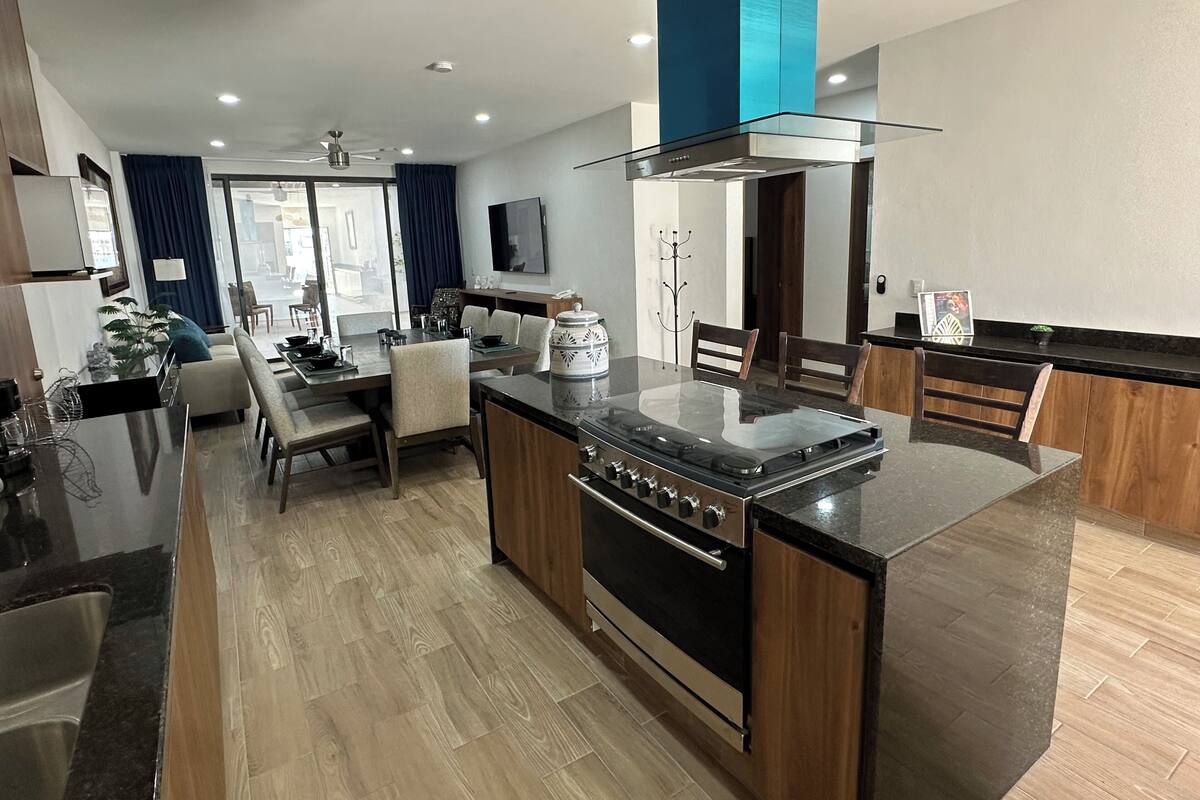 A modern kitchen with a central island, wooden cabinets, and a built-in oven.