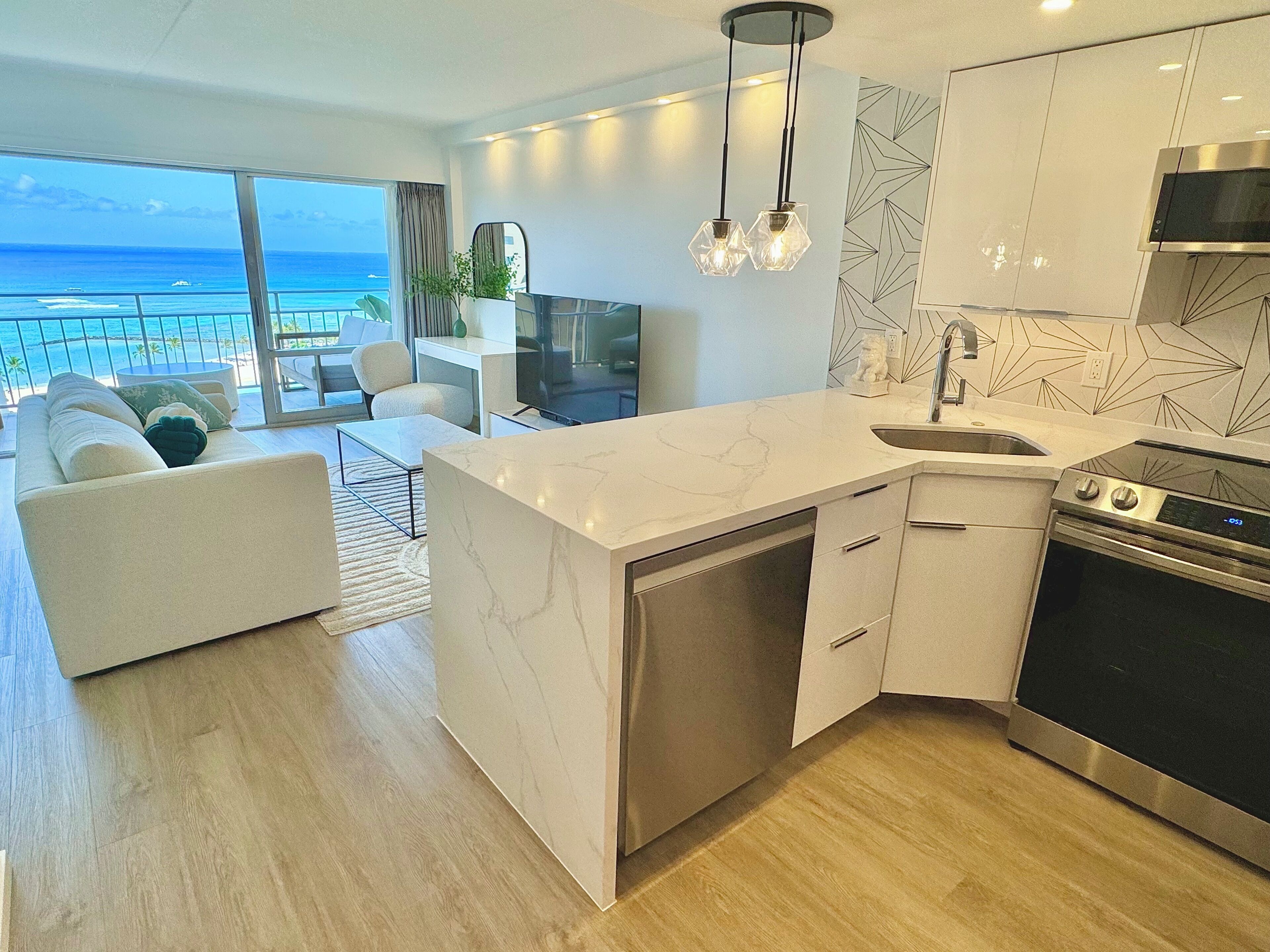 Una cocina moderna con una isla grande, electrodomésticos de acero inoxidable y vista al océano.