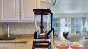 A kitchen with a blender on the counter, two drinks with flowers, and decorative turtle figurines.