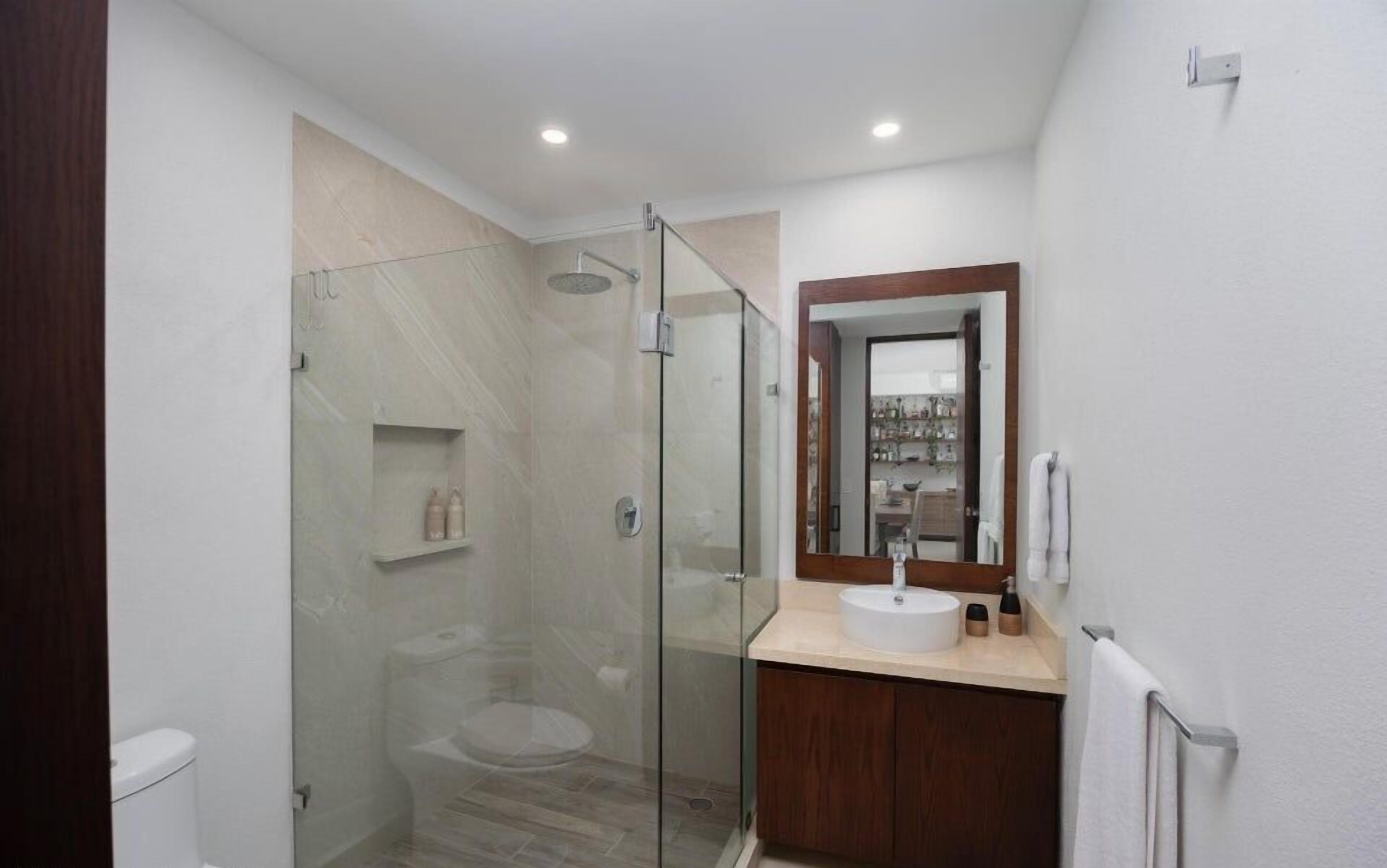 Un bagno moderno con doccia vetrata, un water e un lavabo con specchio.