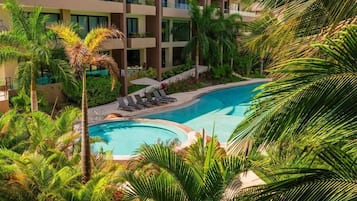 Alberca al aire libre, sombrillas en la alberca y camastros