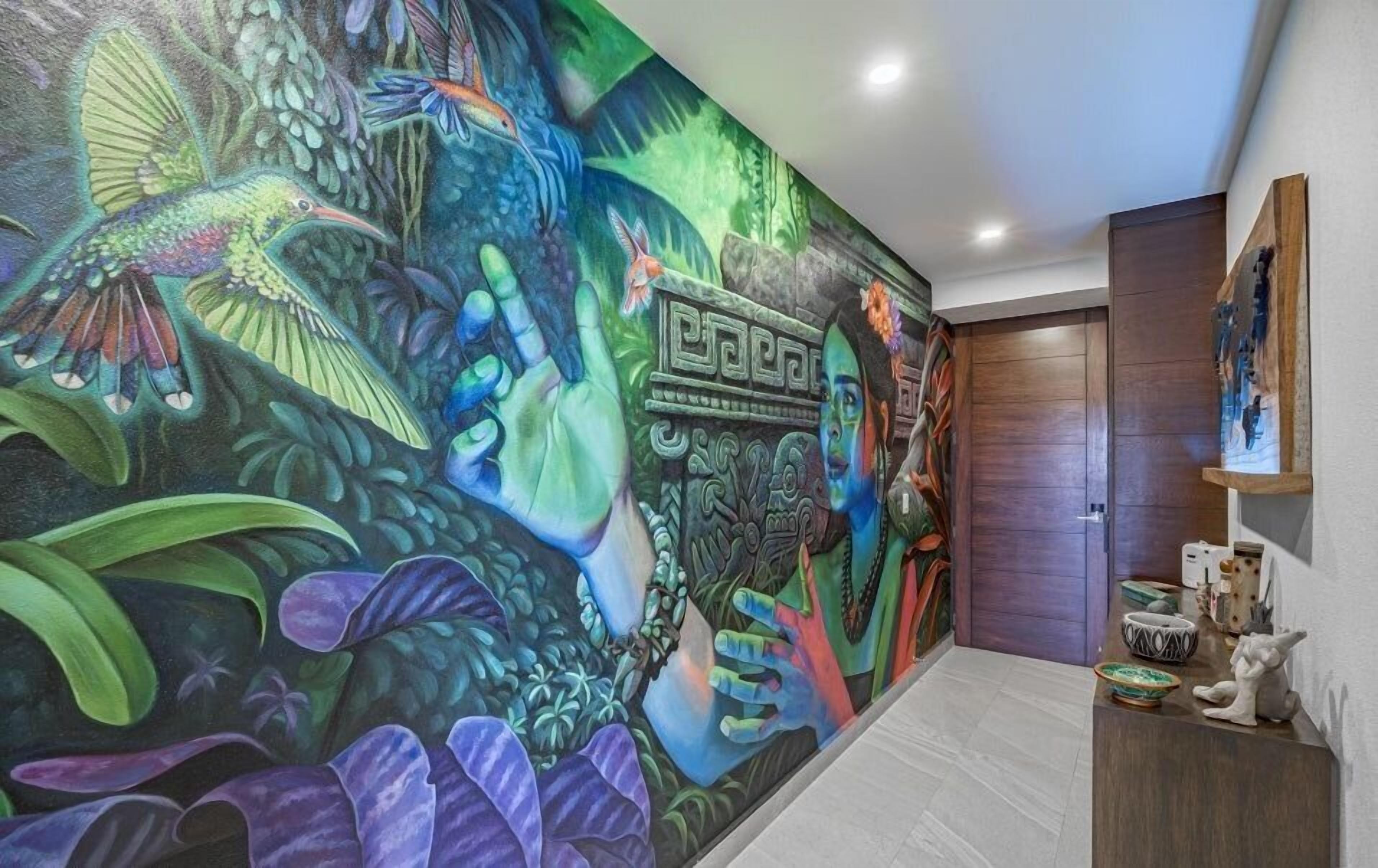 A hallway with a vibrant mural featuring a jungle scene, a stone structure, and a wooden door.