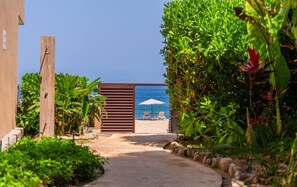A pathway leading to a beach area with two chairs and an umbrella. - Villa Mango 2 bed with jungle view (San Francisco)