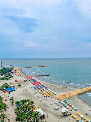 An aerial view of a beach with rows of umbrellas and beachgoers. - For Your Eyes Only - Luxury at sea (Cartagena)