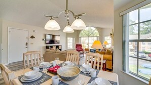 A dining area with a table set for four, a chandelier, and a large window with a view of the street.
