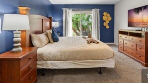 A bedroom with a bed, a ceiling fan, a nightstand, a dresser, and a window with curtains.