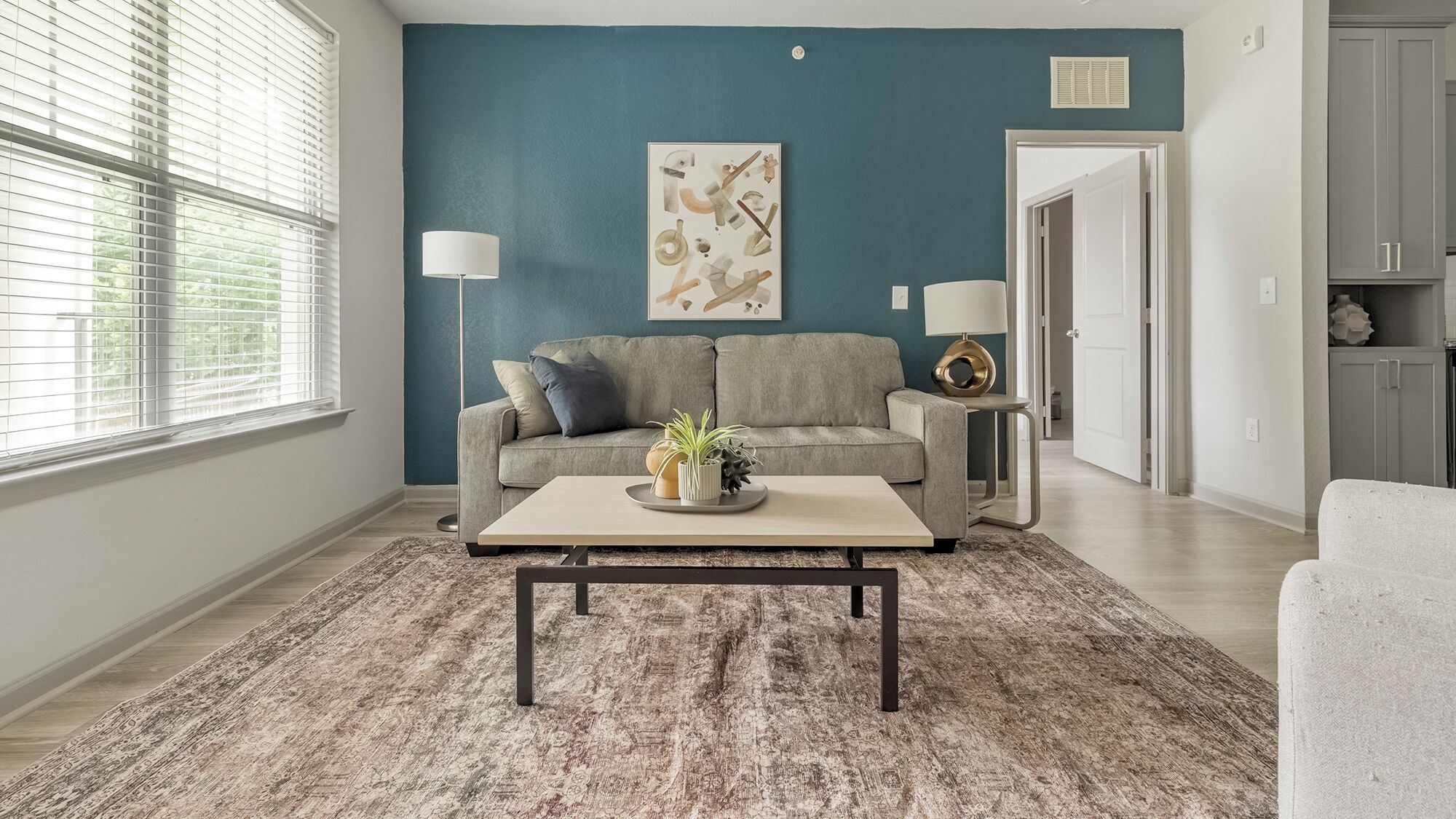 Sala de estar com sofá cinza, mesa de centro e parede azul de destaque.