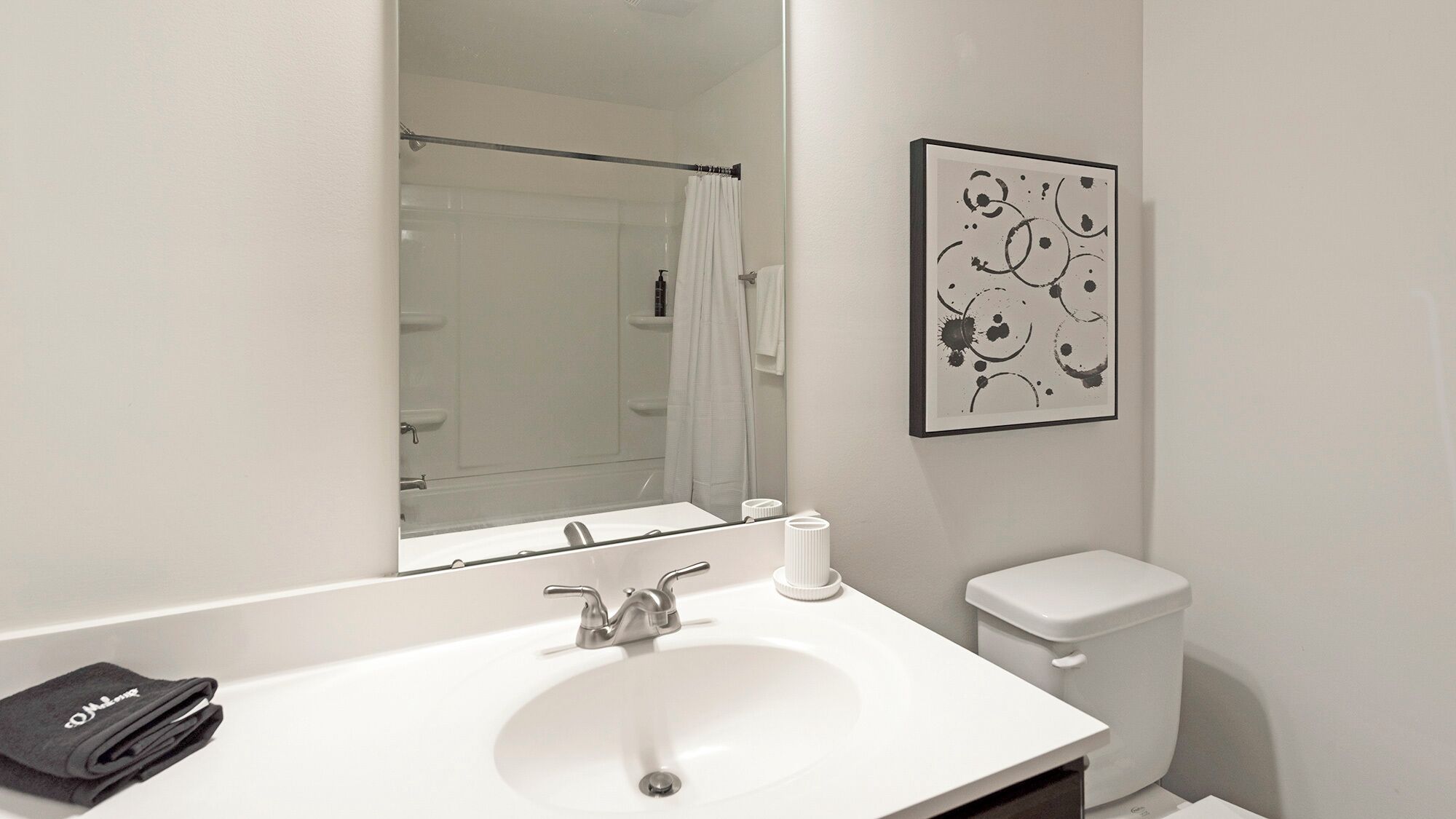 A modern bathroom with a white sink, a toilet, and a shower visible in the background.
