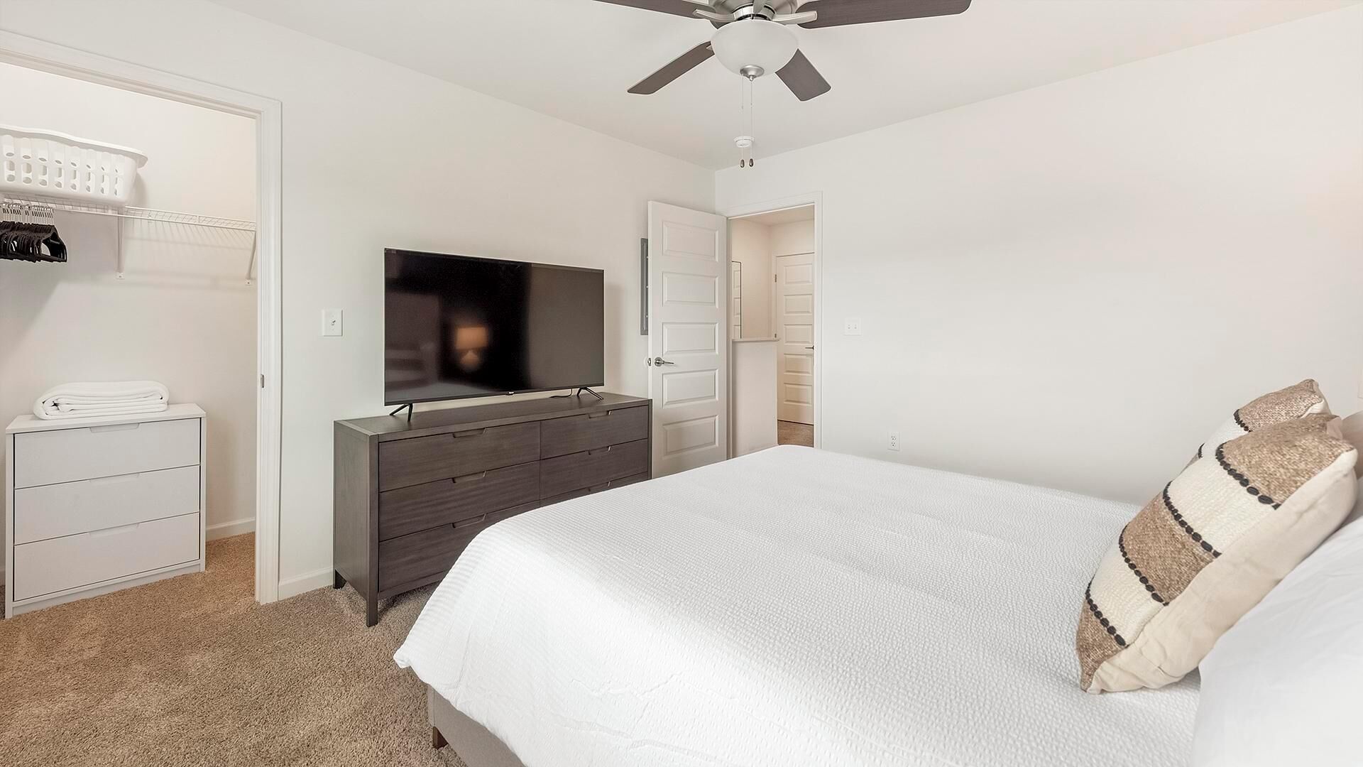 A bedroom with a bed, a dresser, a television, and a closet.