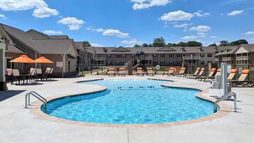 Een seizoensgebonden buitenzwembad, ligstoelen bij het zwembad