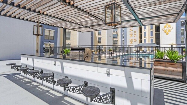 Un espace bar extérieur avec une piscine, des sièges et une pergola.
