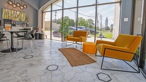 Un intérieur moderne comprenant un coin repas, des chaises jaunes, une grande fenêtre et une vue sur l’extérieur.
