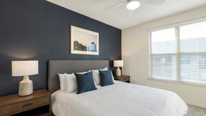 A bedroom with a bed, two bedside tables, a ceiling fan, a window with blinds, and a framed picture on the wall. - Landing Apartments Fort Worth - Charleston (Fort Worth)