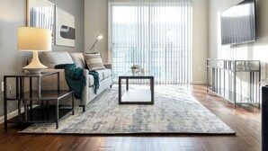 A modern living room with a sofa, a coffee table, a lamp, and a TV. - Landing Apartments Fort Worth - Charleston (Fort Worth)