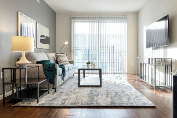 A modern living room with a sofa, a coffee table, a lamp, and a TV.
