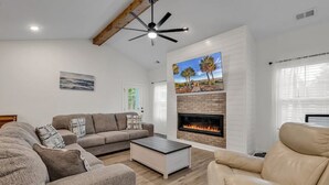 Un salon doté d’une cheminée, d’un ventilateur de plafond et d’une grande fenêtre.