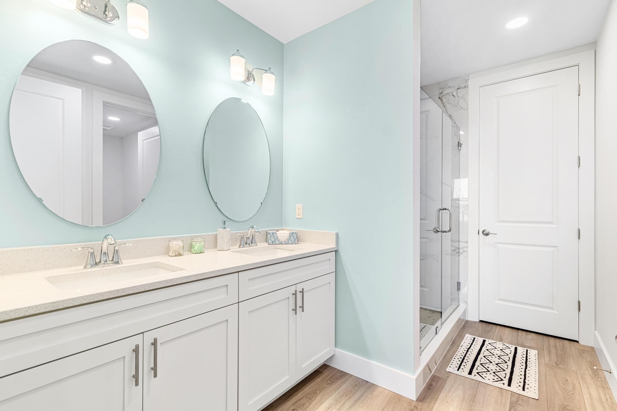 A bathroom with two sinks, a large mirror, and a shower area.