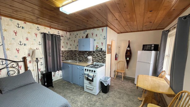 A compact room with a bed, a kitchenette, a dining table, and a chair. - Stoney River Lodge - Unit 7 - Fisherman (Loveland)