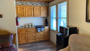 A compact kitchen with wooden cabinets, a stove, a microwave, and a coffee maker. - Stoney River Lodge - Unit 8 - Buffalo (Loveland)