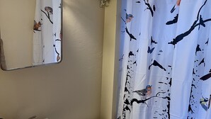 A bathroom with a white sink, two toilets, and a shower curtain with bird patterns.