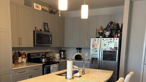 Eine moderne Küche mit einer zentralen Kochinsel, Edelstahlgeräten und einem Kühlschrank mit Magneten.