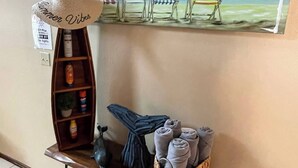 A beach-themed decor with a beach chair, a hat, and towels on a shelf.