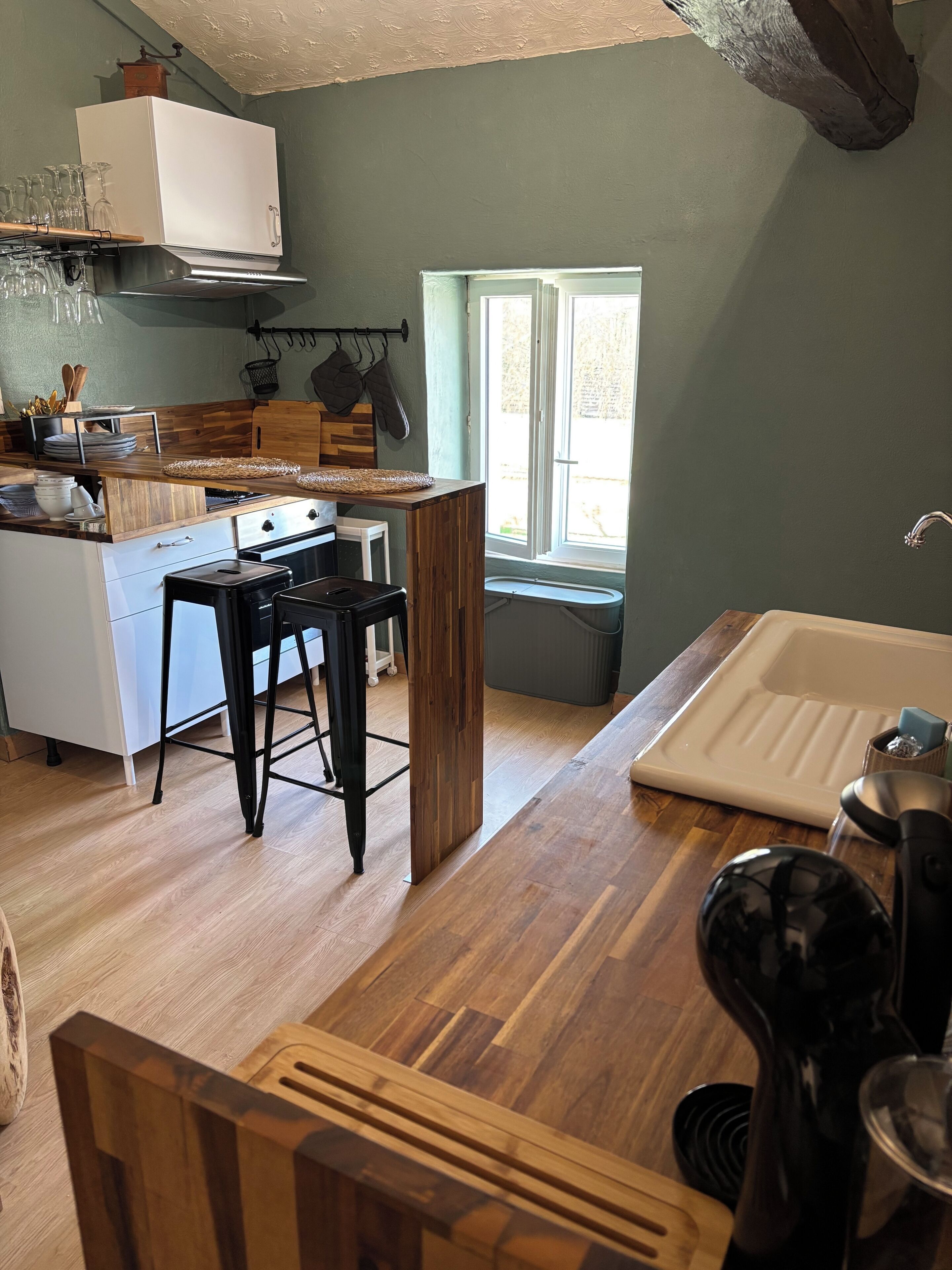 A compact kitchen with a wooden countertop, a sink, and a window providing natural light.