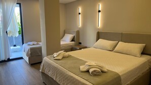 Ein modernes Hotelzimmer mit einem großen Bett, einem Nachttisch, einem Sessel und einem Fenster mit Vorhängen.