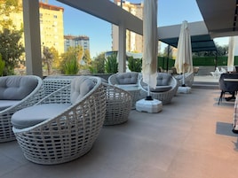 A covered outdoor seating area with wicker furniture and umbrellas.
