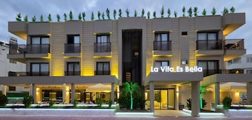 A multi-story hotel with a modern design, featuring balconies and a central entrance.
