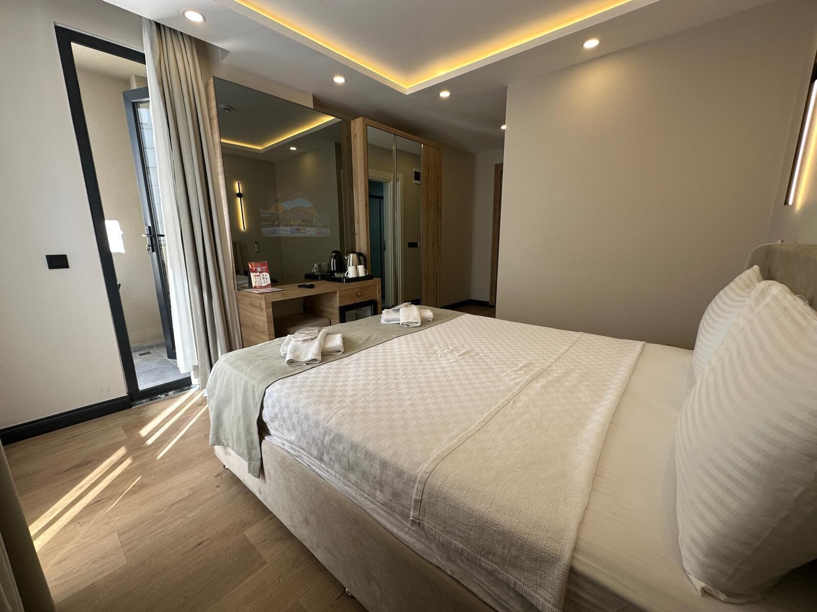 Una habitación de hotel moderna con una cama grande, un escritorio, un espejo y zona de ducha.