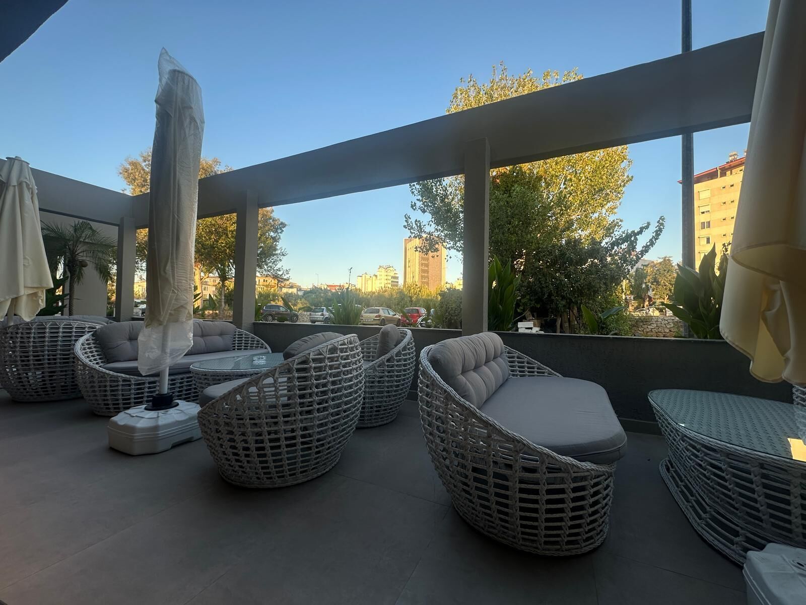 Una terrazza sul tetto con mobili in vimini e ombrelloni, che offre una vista sulla città.