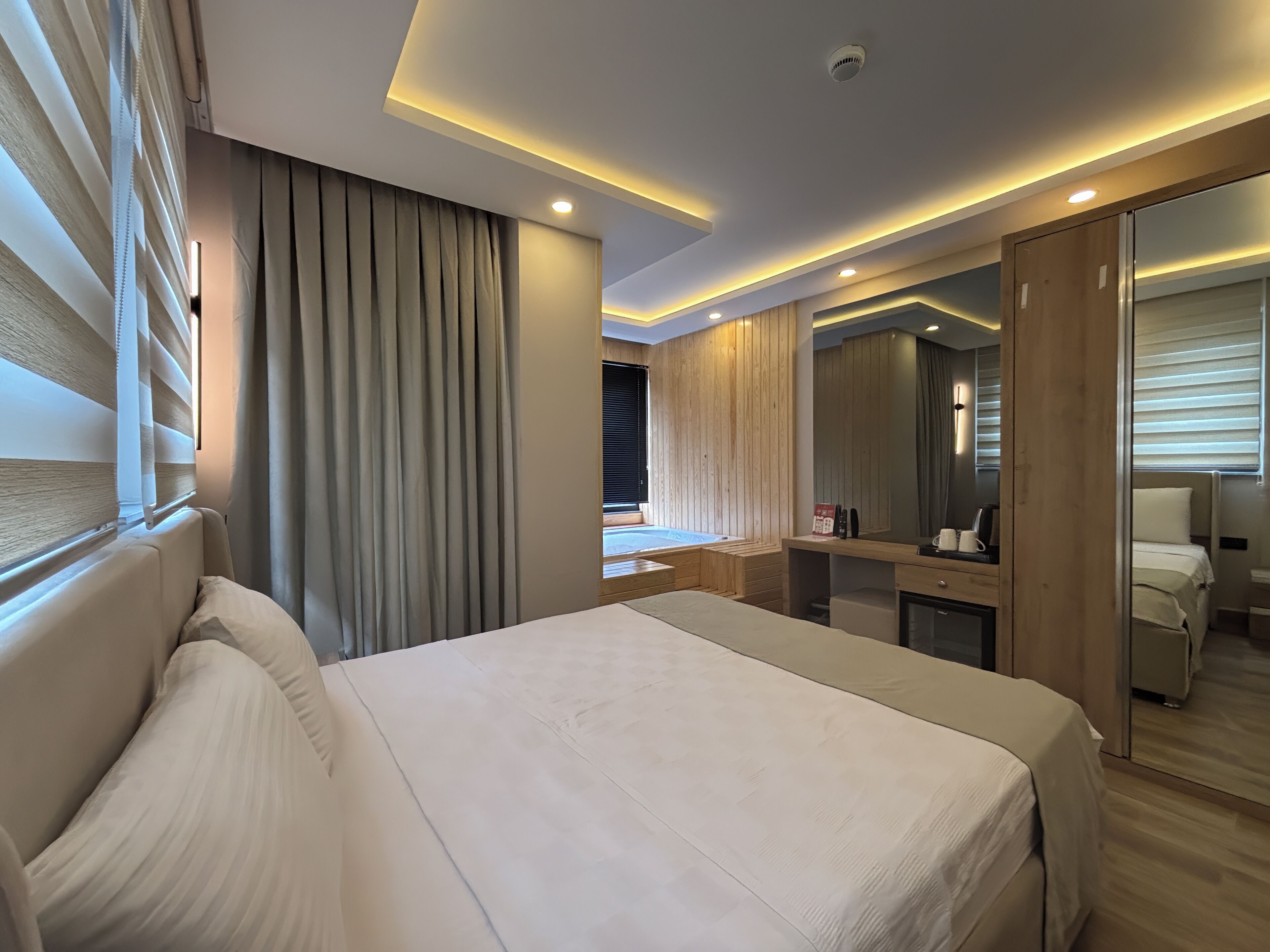 Une chambre d’hôtel moderne équipée d’un grand lit, d’un bureau, d’un miroir et d’un espace douche.