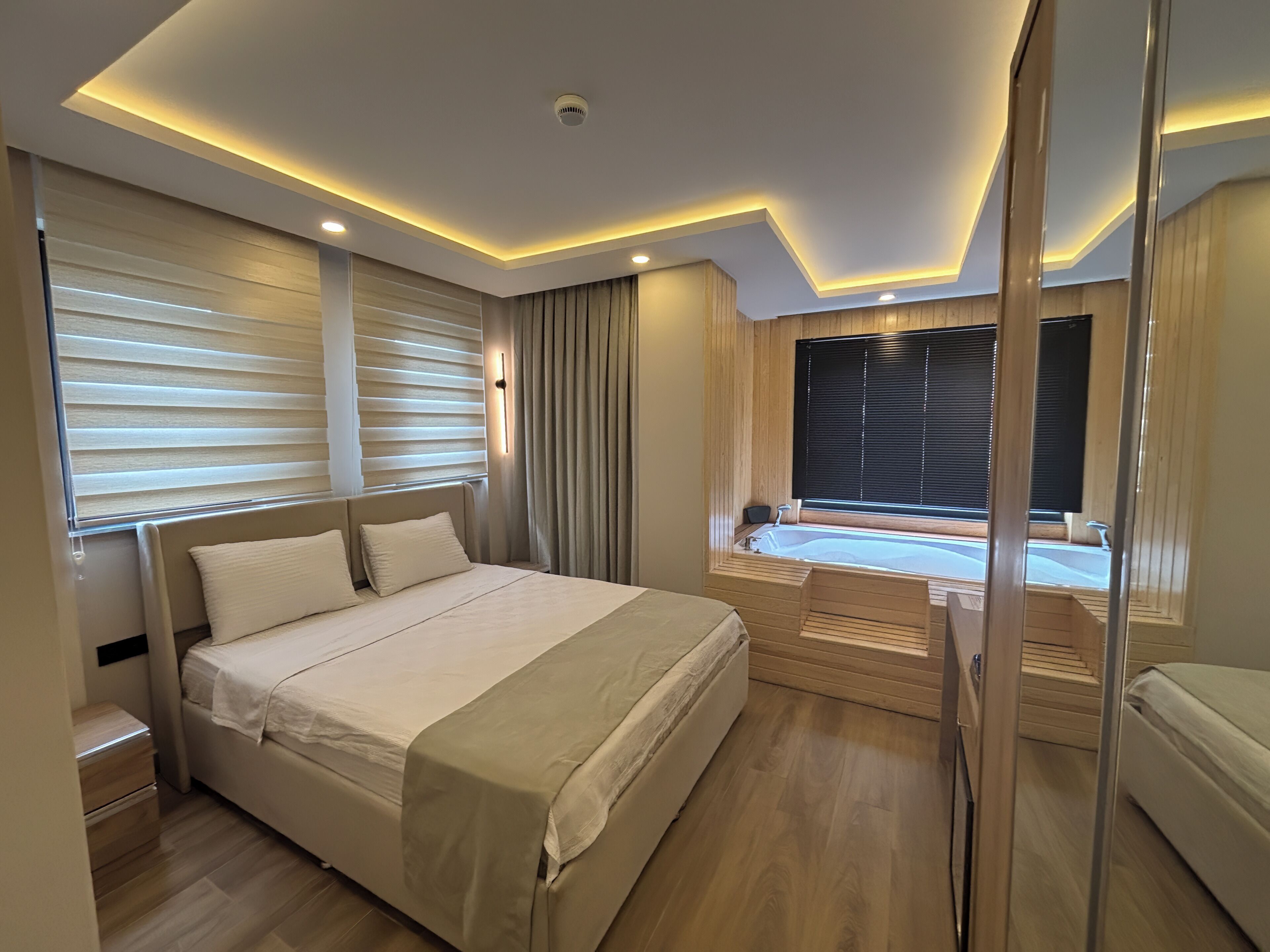 Un dormitorio moderno con una cama grande, una bañera integrada y un gran ventanal corredera.