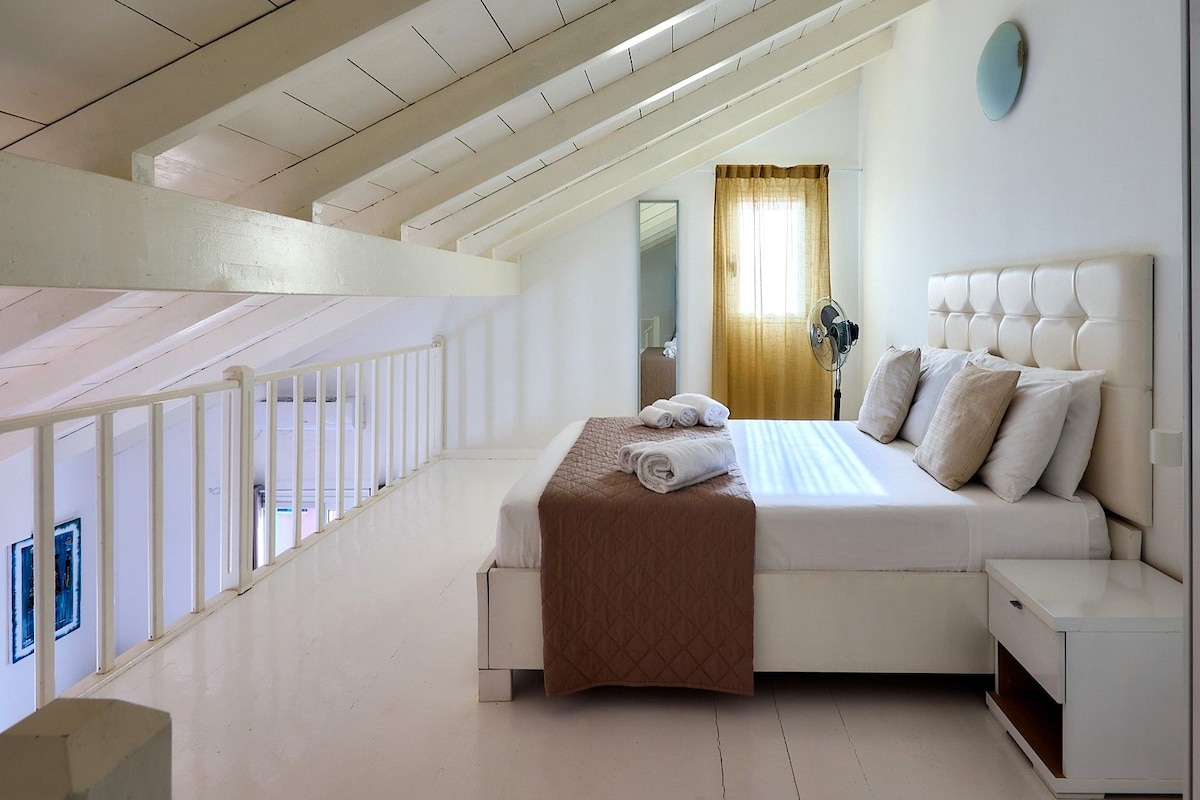 Habitación de hotel con cama, mesita de noche y vistas al exterior.